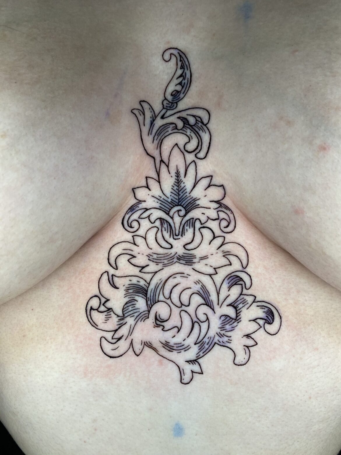 A simple art deco sternum tattoo done in minimalist style by Basic Urban Witch Tattoo and Tarot in Fort Collins Colorado.